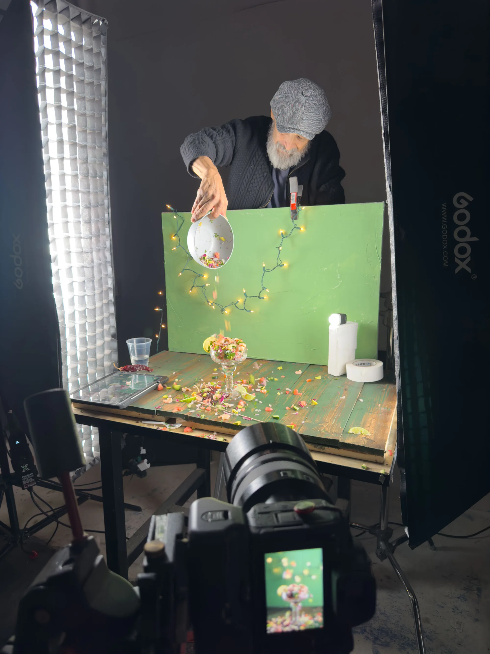 Photographer sprinkling colorful garnishes onto a plated dish on a green studio backdrop - Raging Bull Food Photography