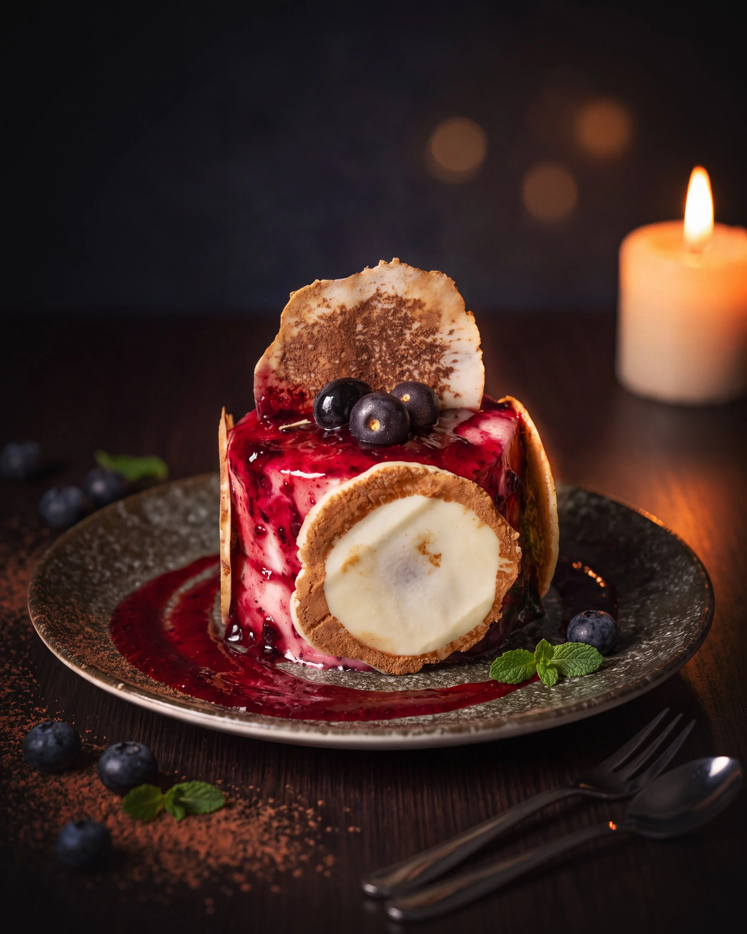 Blueberry dessert with ice cream, berry sauce, and a candle