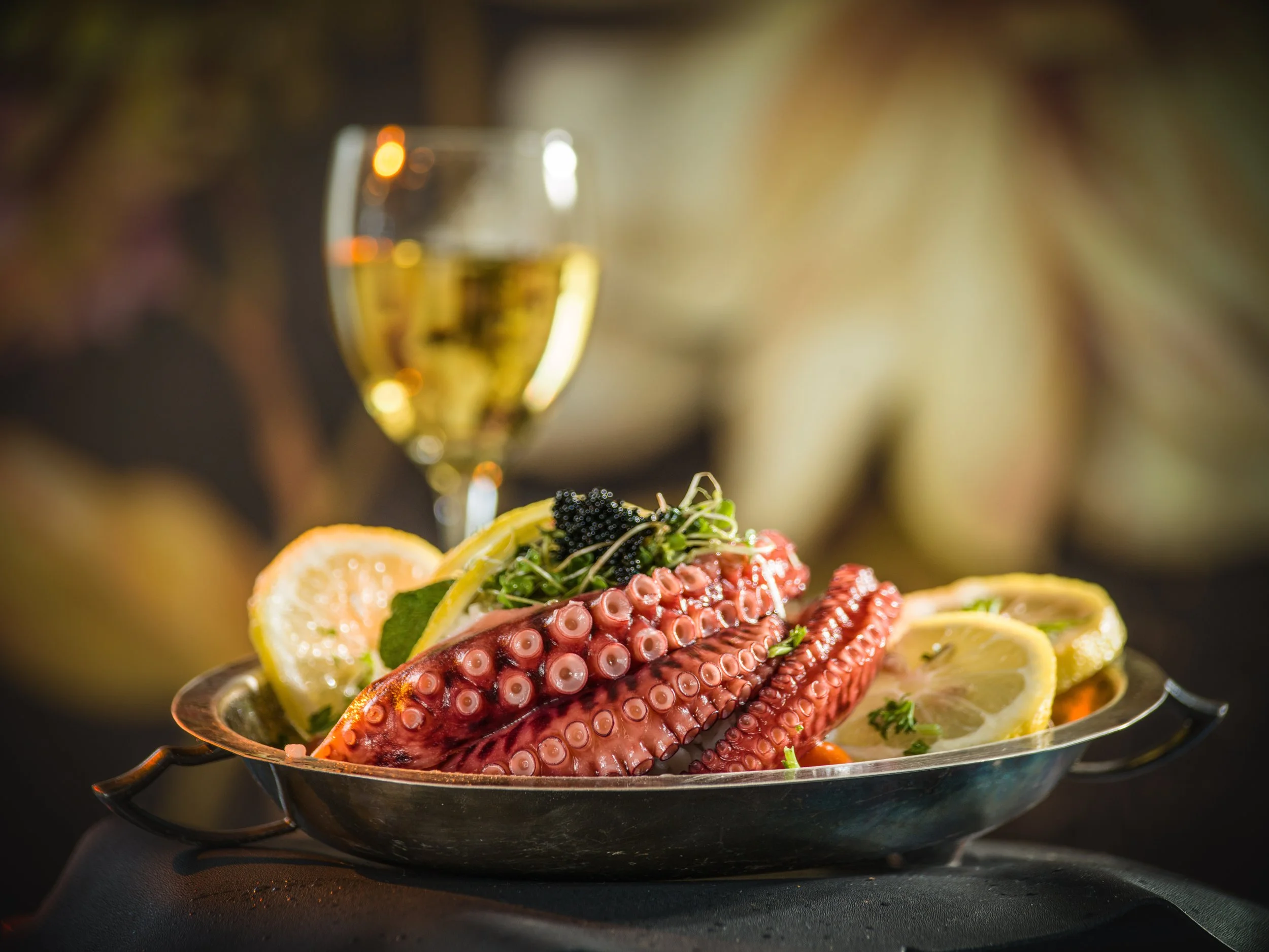 Grilled octopus with lemon wedges and a glass of white wine