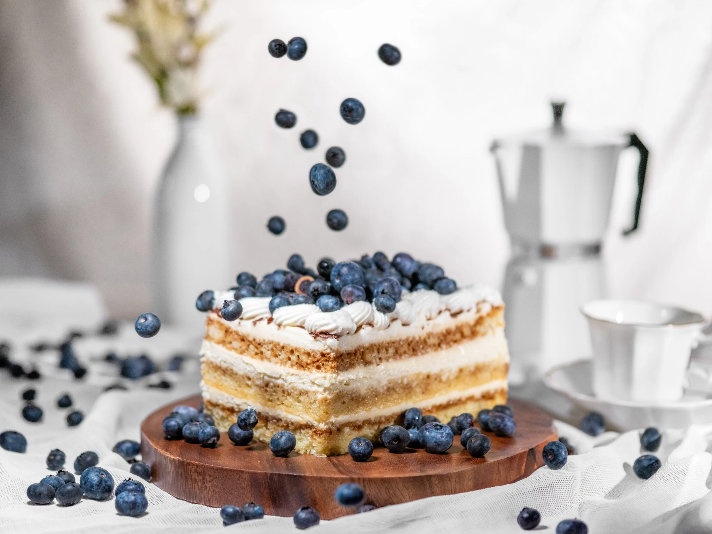 Sliced blueberry layer cake with blueberries falling above it