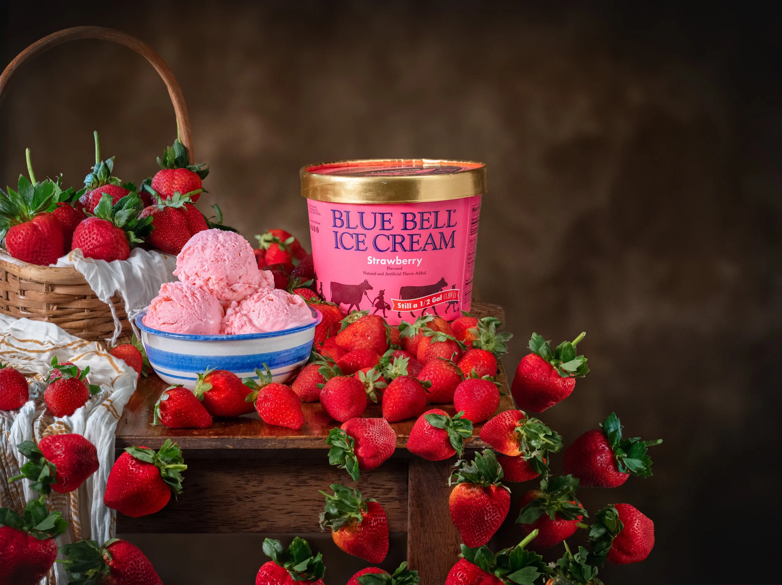 Blue Bell strawberry ice cream with a bowl of scoops and fresh strawberries