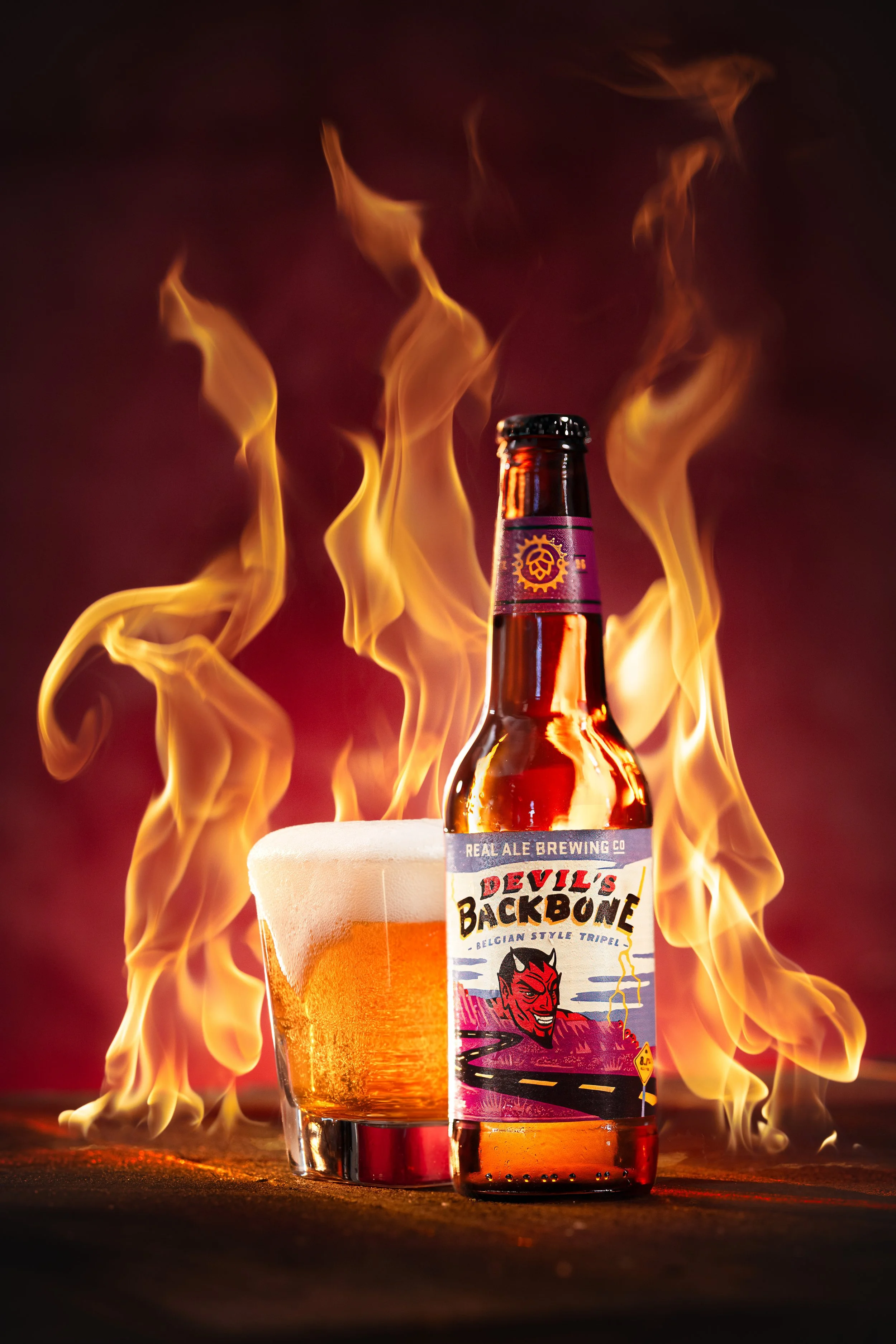 Devil's Backbone beer bottle and glass in front of flames