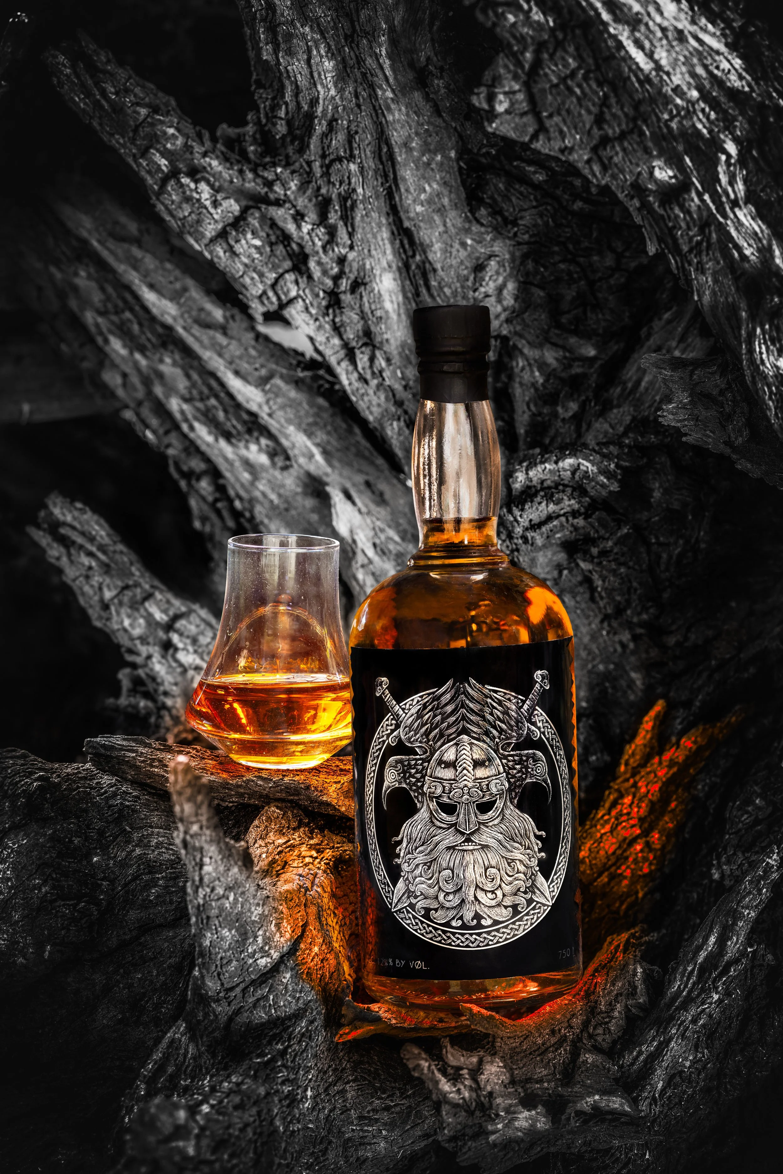 Whiskey bottle and glass on charred wood