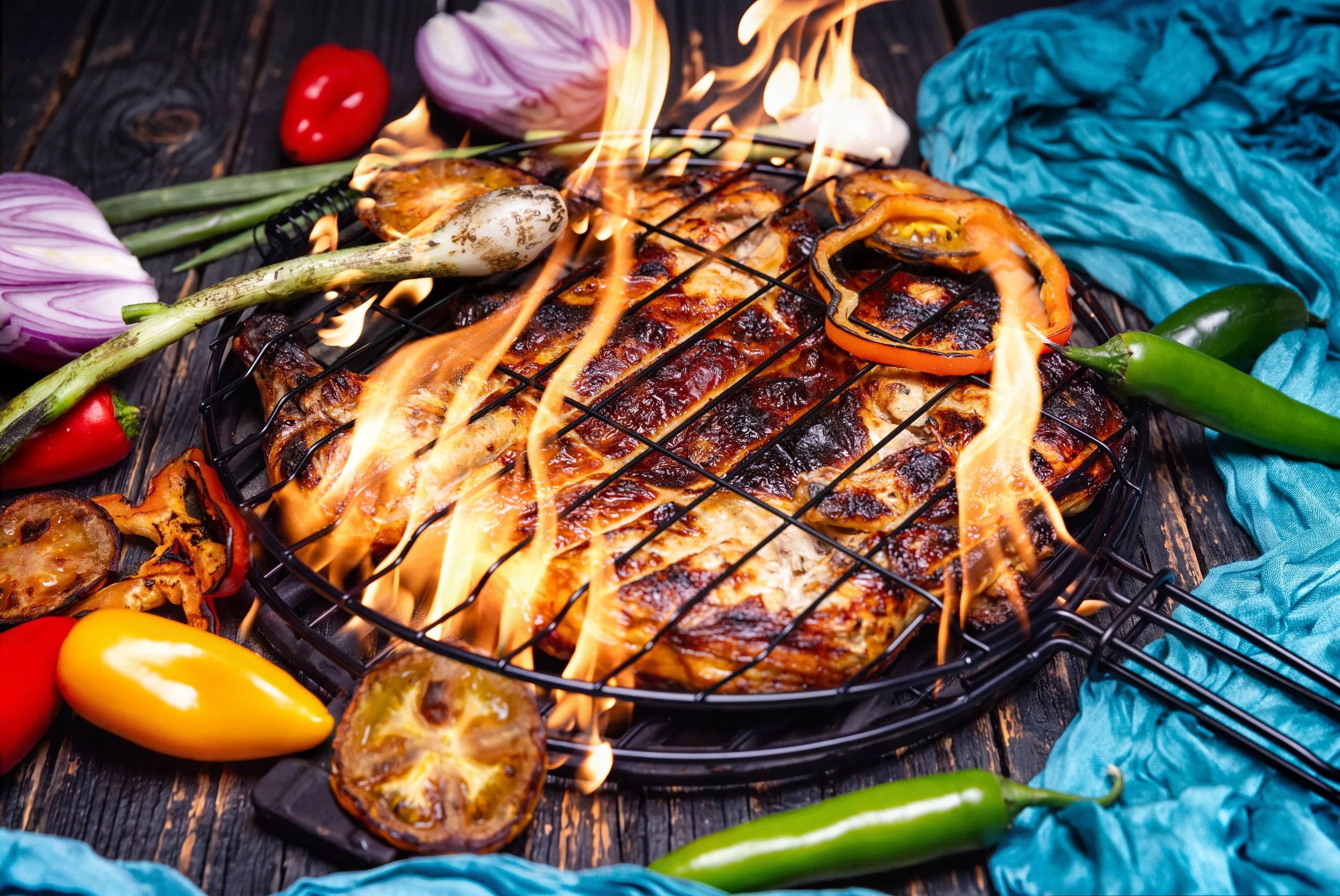 Chicken grilling over open flames with peppers
