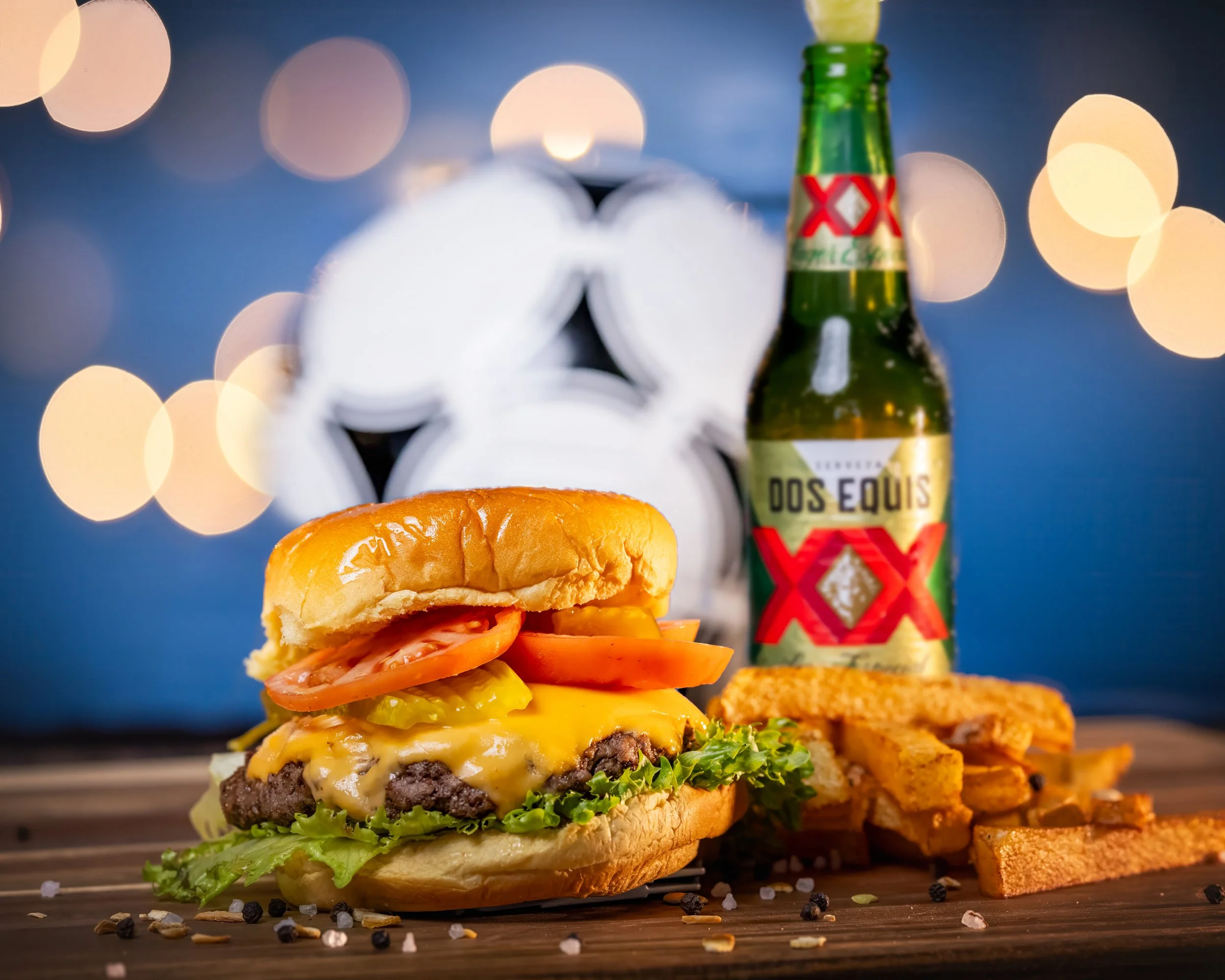 Burger with Dos Equis beer and fries on a wooden table