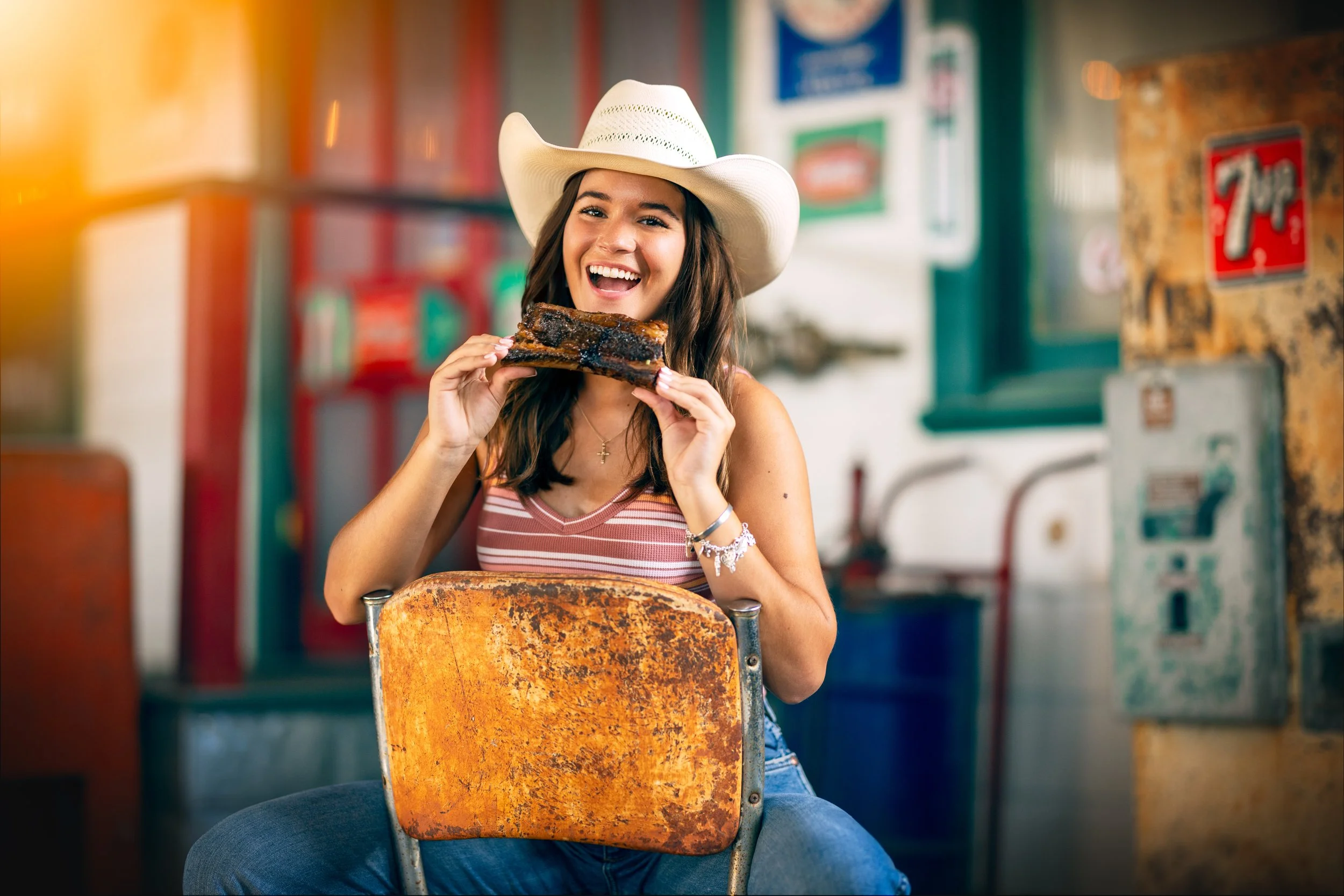 Woman in a cowboy hat eating a rib at a gas station