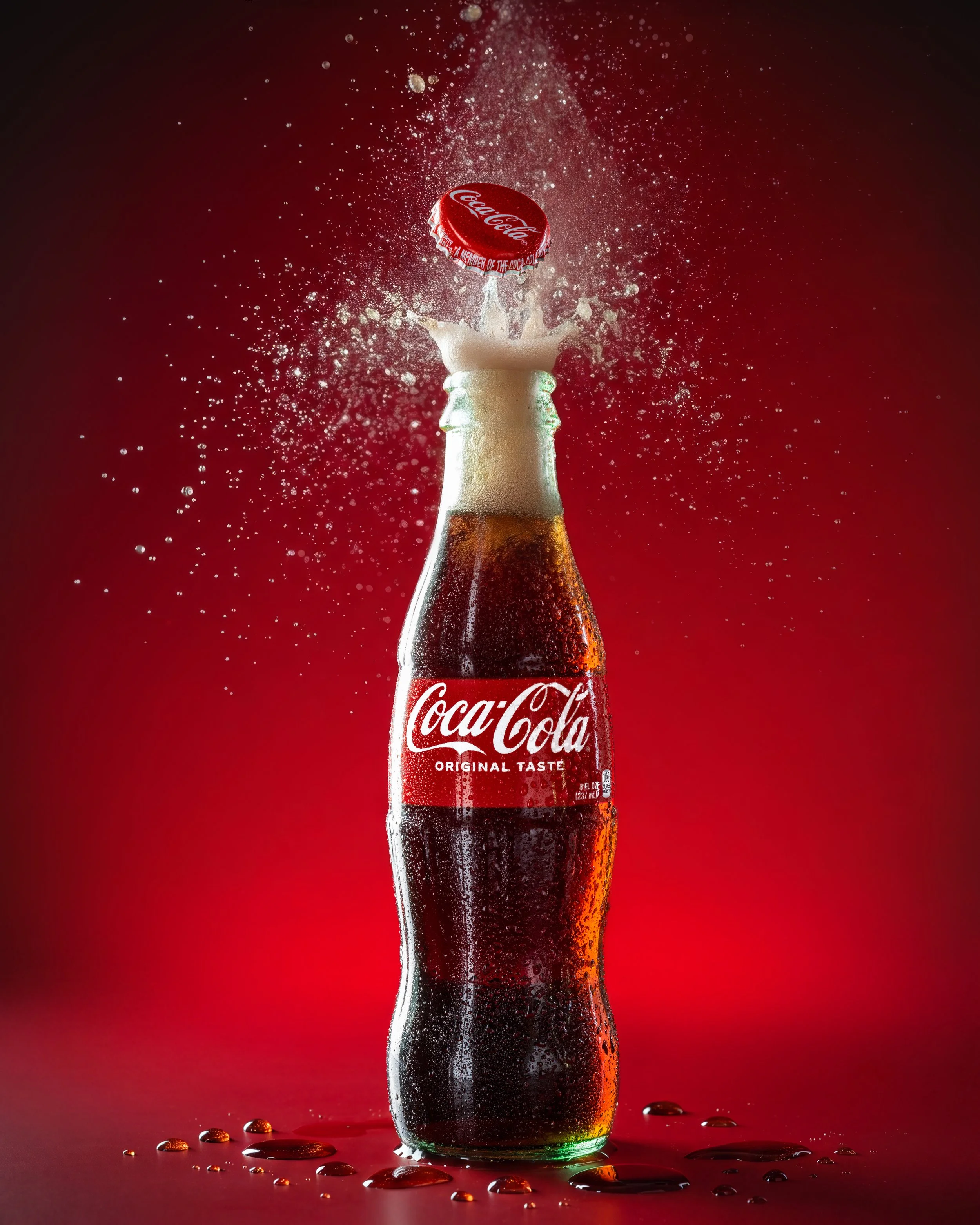 Coca-Cola bottle with its cap popping off against a red background