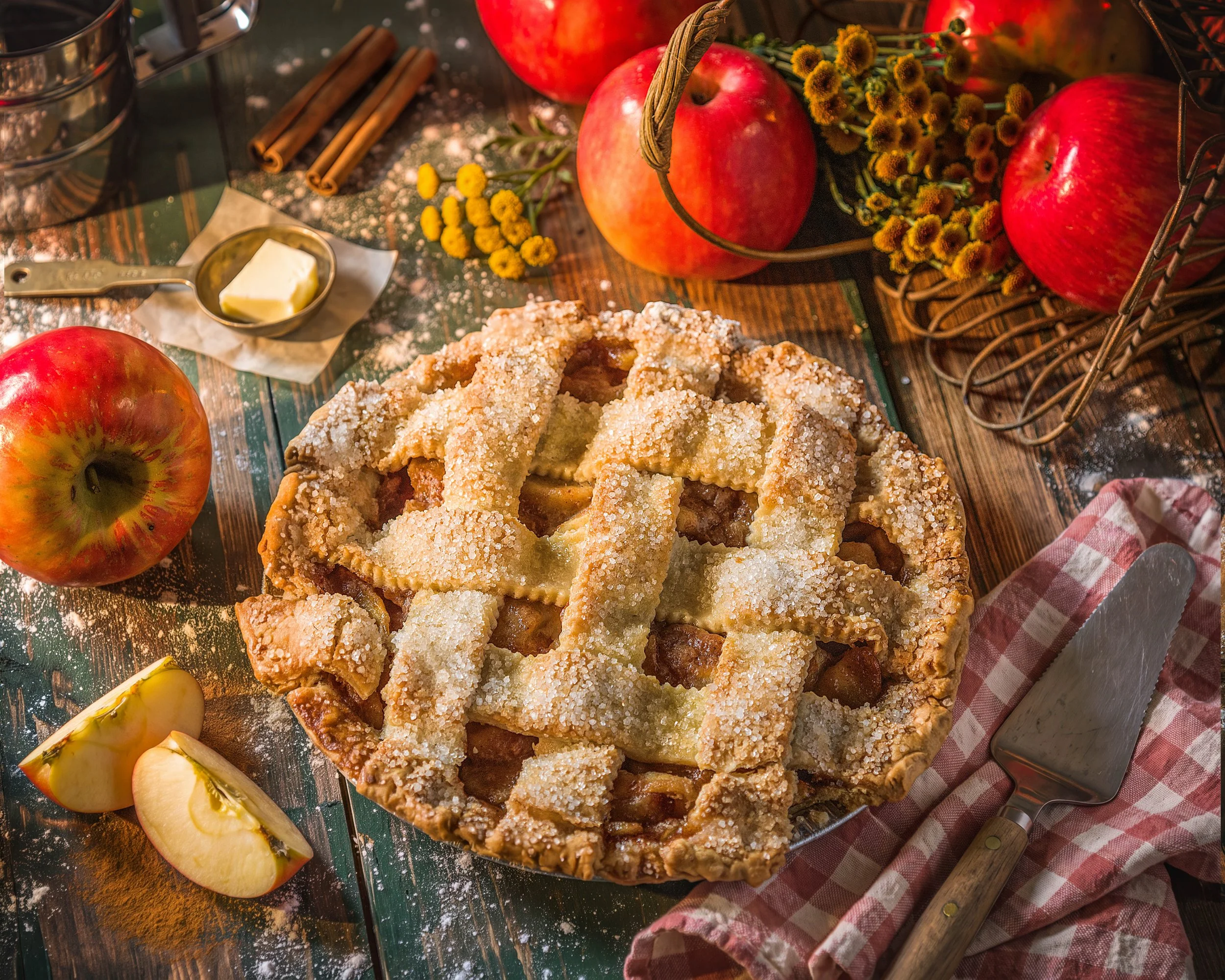 Lattice apple pie with powdered sugar on a rustic table with apples